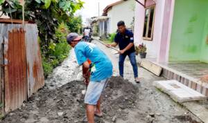 Foto: Ketua SMSI Binjai-Langkat mengenakan kaos hitam memegang cangkul membantu Warga Masyarakat terdampak bajir.
