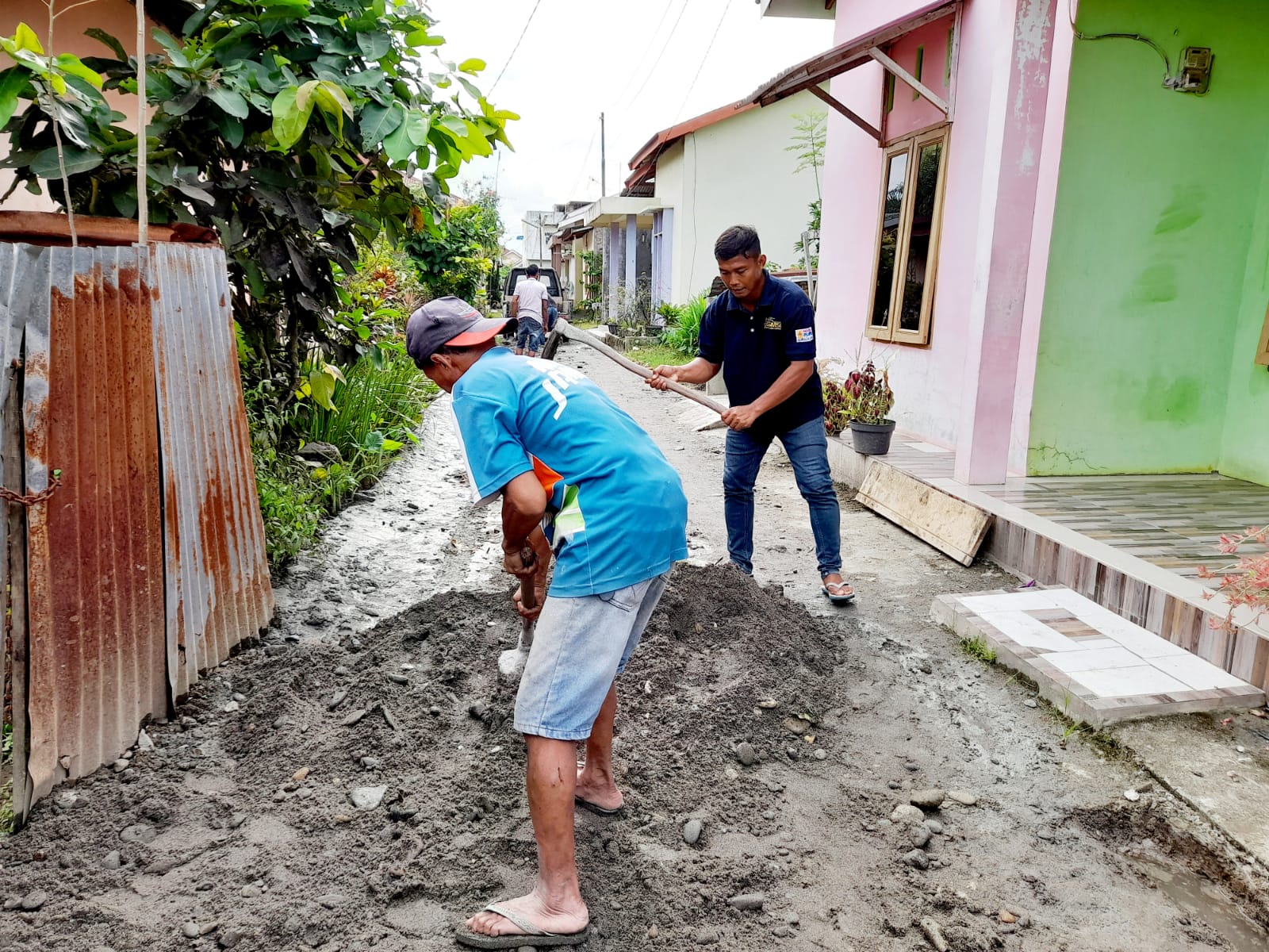Foto: Ketua SMSI Binjai-Langkat mengenakan kaos hitam memegang cangkul membantu Warga Masyarakat terdampak bajir.